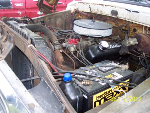 1973 Ford F-250 - Engine bay of a 1973 Ford F-250, aftermarket Edelbrock components and a visible battery.