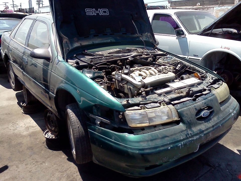 Green Ford Taurus SHO with hood open, showing engine. Front passenger side is damaged