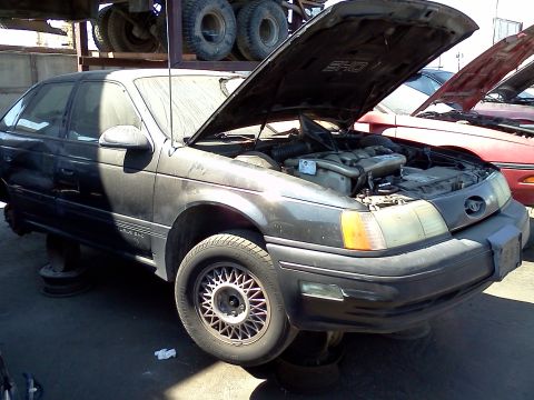 1993 Ford Taurus - This 1993 Ford Taurus SHO is in a junkyard with its hood open, revealing the engine.