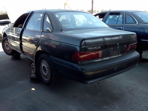 1993 Ford Taurus - Junkyard 1993 Ford Taurus with doors open and wheels off, another vehicle behind.