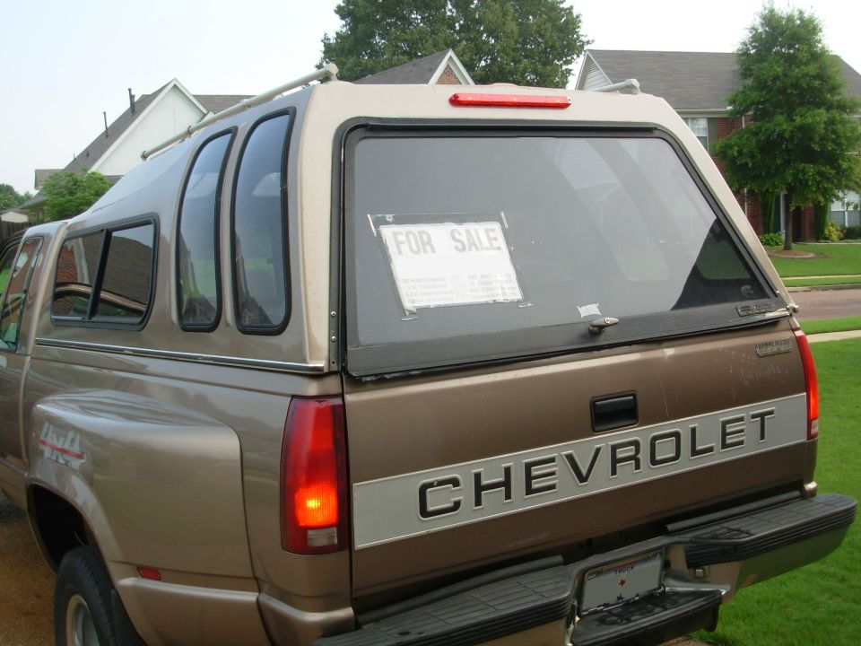 Brown Chevrolet pickup with camper shell and For Sale sign in rear window