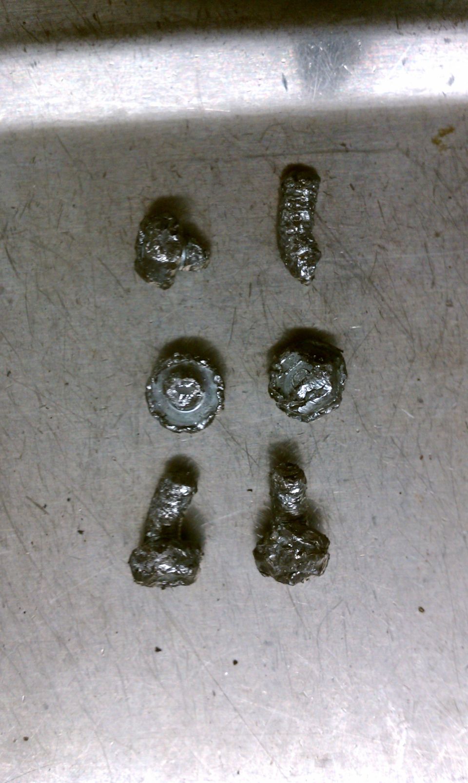 Six pieces of metal slag on a textured surface