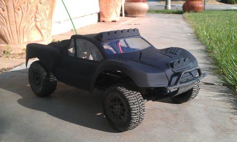 1992 Ford Ranger - A black remote control monster truck sits on a paved surface next to a grassy area.