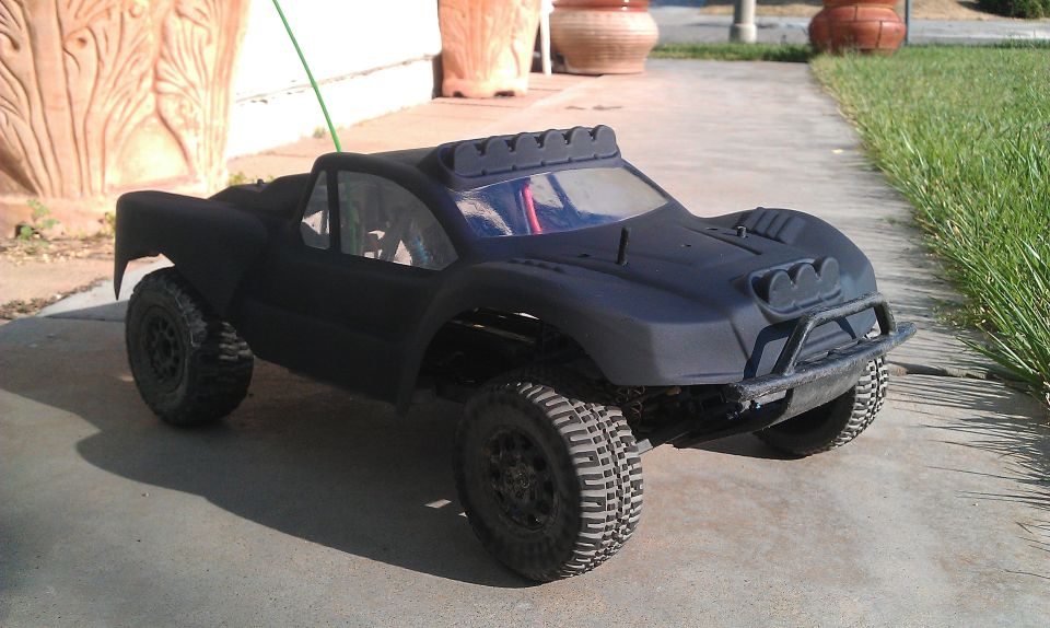 black remote control monster truck with off-road tires parked on concrete