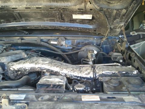 1995 Ford Bronco - Engine bay of a 1995 Ford Bronco, an intake manifold insulated with aluminum foil.