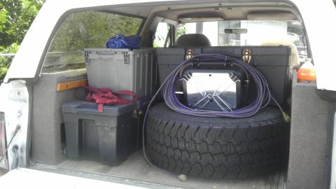 1989 Ford Bronco - Storage bins and a spare tire are loaded into the cargo area of a vehicle.