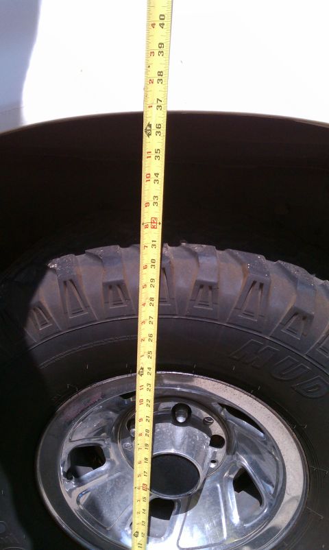 1990 Ford Bronco - Measuring tape is placed next to a tire and rim for scale.
