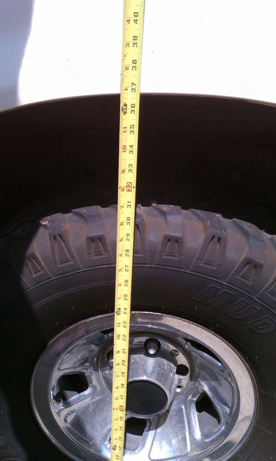 Measuring tape against a tire and rim, showing height measurement