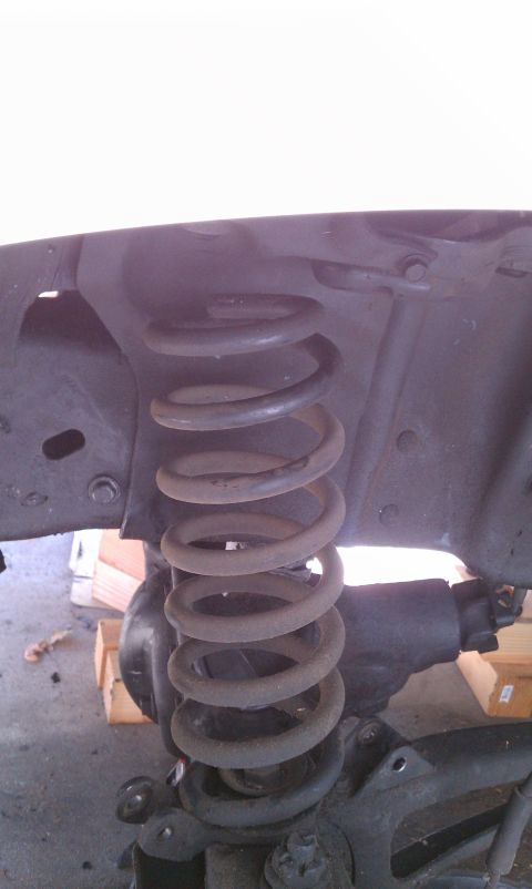 1990 Ford Bronco - Close-up of a vehicle's front suspension coil spring and its surrounding components.