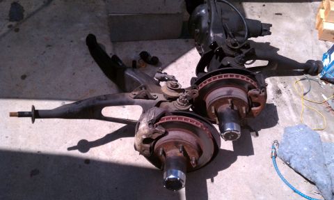 1990 Ford Bronco - Vehicle suspension and axle parts are laid out on the ground, possibly for repair or modification.