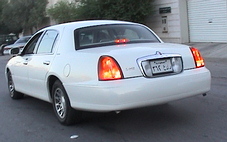 2002 Lincoln Town Car - A white 2002 Lincoln Town Car is seen from the rear, with its brake lights on.