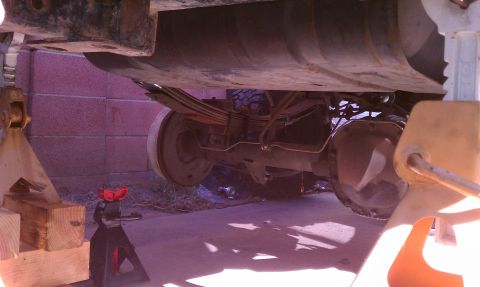 1990 Ford Bronco - The underside of a vehicle is supported by jack stands, revealing its rear axle and suspension components.