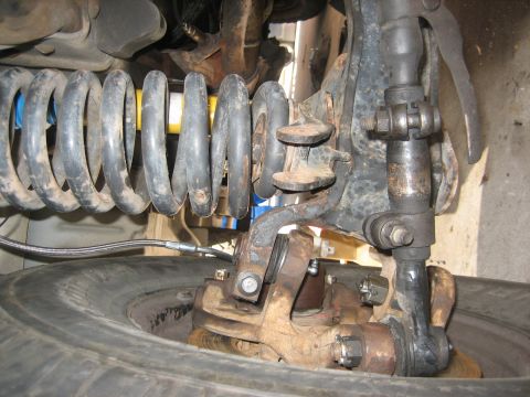 1990 Ford Bronco - Detailed view of the front suspension system and tire, showing mechanical components.