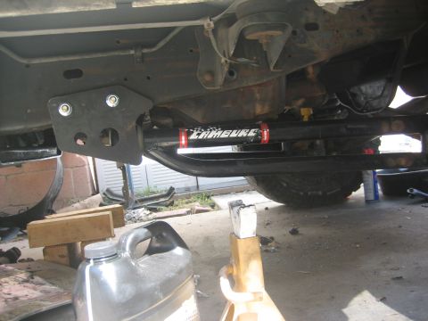 1990 Ford Bronco - Vehicle undercarriage with a steering stabilizer installed, showing a black mounting bracket.