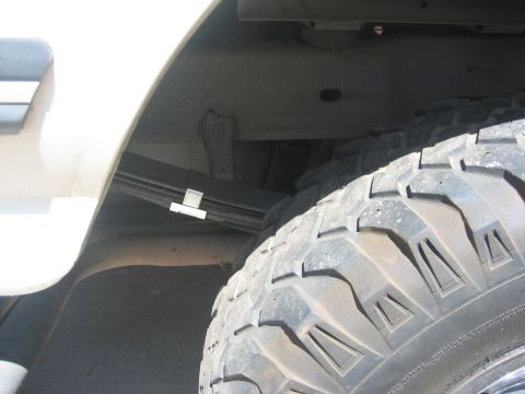 1990 Ford Bronco - This image shows the rear suspension and a tire of a vehicle, with a watermark from SuperMotors.net.
