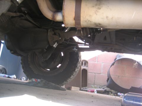 1990 Ford Bronco - The underside of a vehicle is visible, with a large muffler and exhaust pipes.