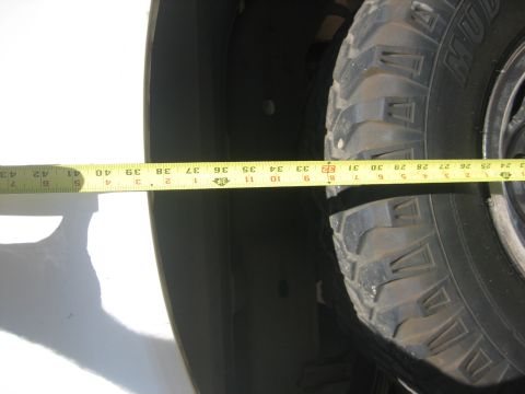 1990 Ford Bronco - A measuring tape is used to measure the wheel well of an unidentified vehicle.