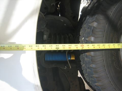1990 Ford Bronco - Measuring suspension components with a yellow tape measure, revealing a blue shock absorber.