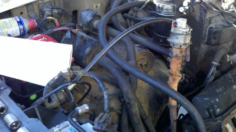 1990 Ford Bronco - Close-up view of a cluttered engine bay with various hoses and electrical components visible.