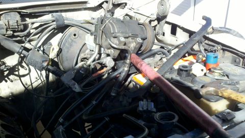 1990 Ford Bronco - The engine bay of a vehicle, the air conditioning compressor and various hoses. Text from a watermark is visible at the bottom.