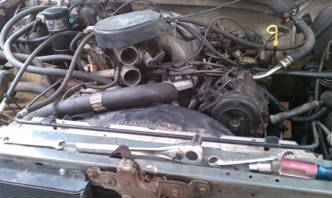 1990 Ford Bronco - Engine bay components and tools are visible, with 'CAUTION FAN' text on a shroud.