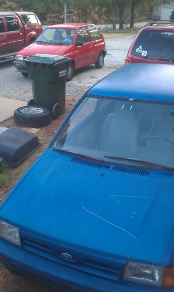 1991 Ford Festiva - Front view of a blue 1991 Ford Festiva parked outdoors with other vehicles.