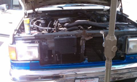 1990 Ford Bronco - The engine compartment of a truck is open for inspection, revealing the mechanical parts within.