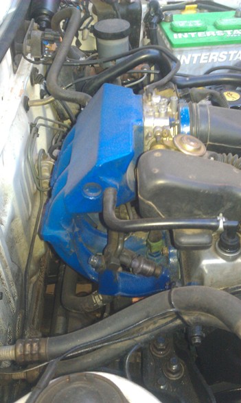 1991 Ford Festiva - Close-up view of an engine bay, highlighting a blue-painted intake manifold and various hoses and components.