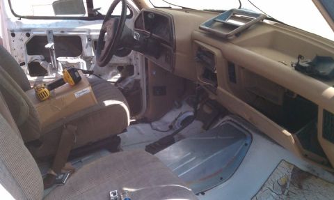 1990 Ford Bronco - The interior of a 1990 Ford Bronco shows significant disassembly, with exposed wiring and missing door panels.