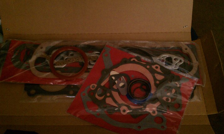 Engine gasket set in packaging, with red and grey gaskets visible