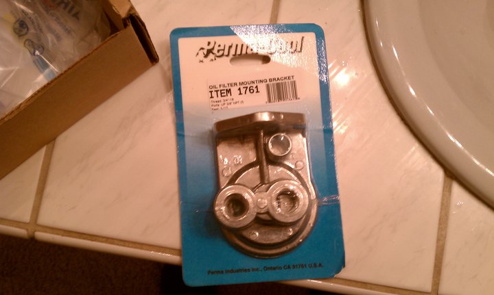 Oil filter mounting bracket in packaging, item 1761, on tiled surface