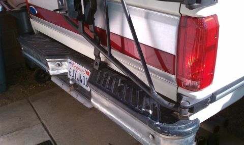 1990 Ford Bronco - This image shows the rear of a white and red truck, a spare tire carrier and a California license plate.