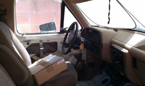 1990 Ford Bronco - The interior of a vehicle, possibly undergoing repairs, with a cardboard box placed on the passenger seat.