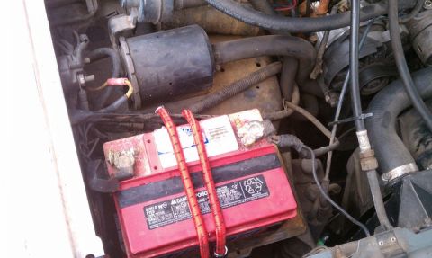 1990 Ford Bronco - Close-up view of a vehicle's engine compartment, focusing on the battery and surrounding components.