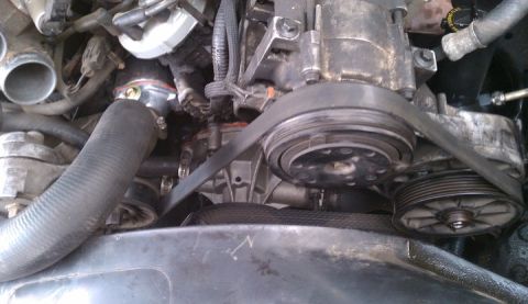 1990 Ford Bronco - Close-up view of engine components, including hoses, belts, and pulleys, in a vehicle's engine bay.
