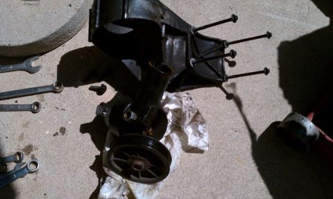 1990 Ford Bronco - A disassembled power steering pump sits on a concrete surface with various tools nearby.