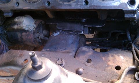 1990 Ford Bronco - The starter motor and its mounting bracket are visible in this close-up engine component shot.