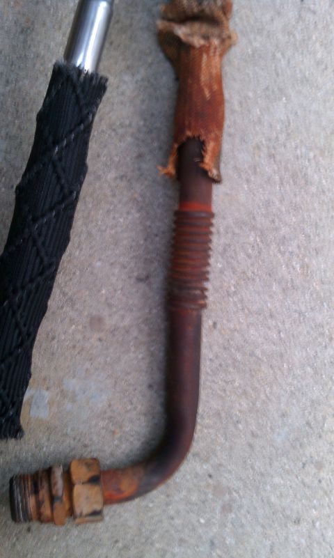 1990 Ford Bronco - A corroded automotive pipe with protective coverings lies on a concrete surface.