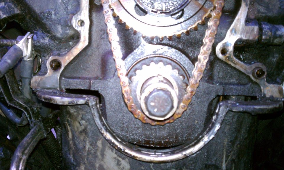 Close-up of engine timing chain and gears, showing wear on the chain