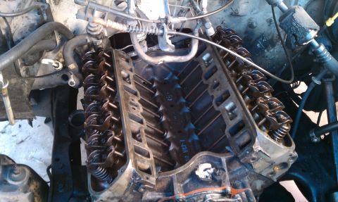 1990 Ford Bronco - Close-up view of a disassembled engine, revealing internal components like rocker arms and springs.