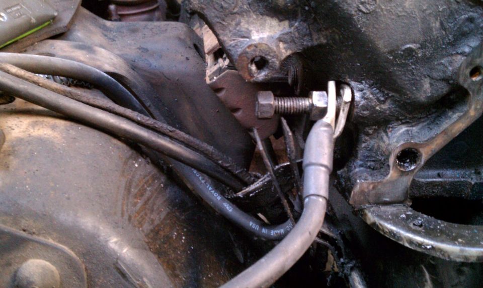Close-up of engine block with bolt and wiring. Text on wire reads 'ROYAL TRON'