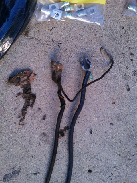 1990 Ford Bronco - Old and new battery terminals and cables are laid out on a concrete surface.