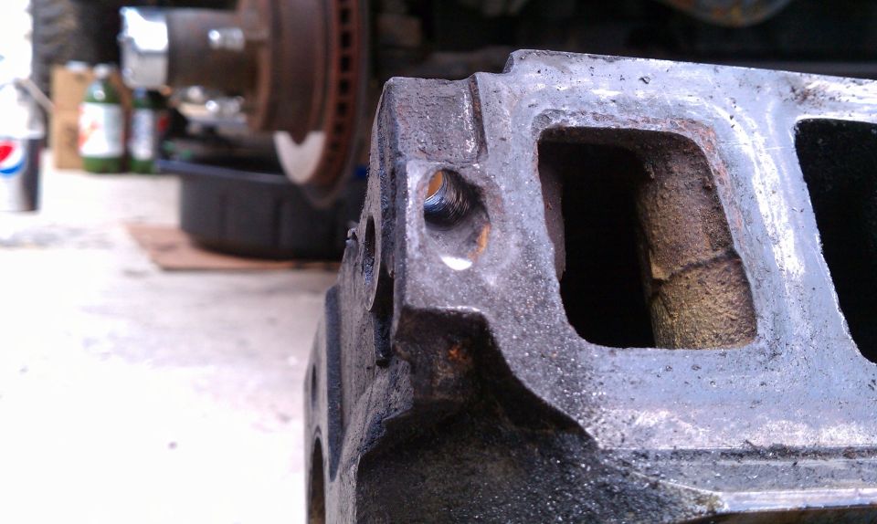 Close-up of a cast iron engine manifold with Supermotors.net watermark