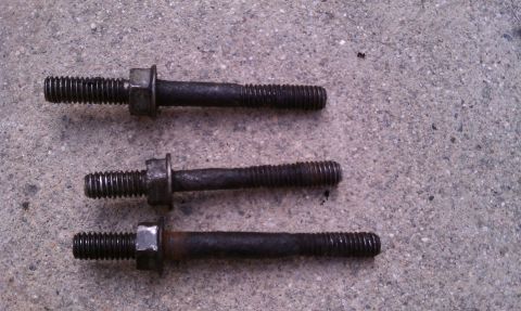 1990 Ford Bronco - Three used threaded bolts with nuts are shown on a concrete surface.