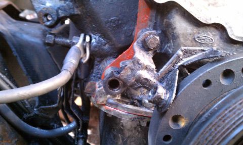 1990 Ford Bronco - A close-up view of a greasy engine bracket, showing a Ford logo and part of a pulley system.