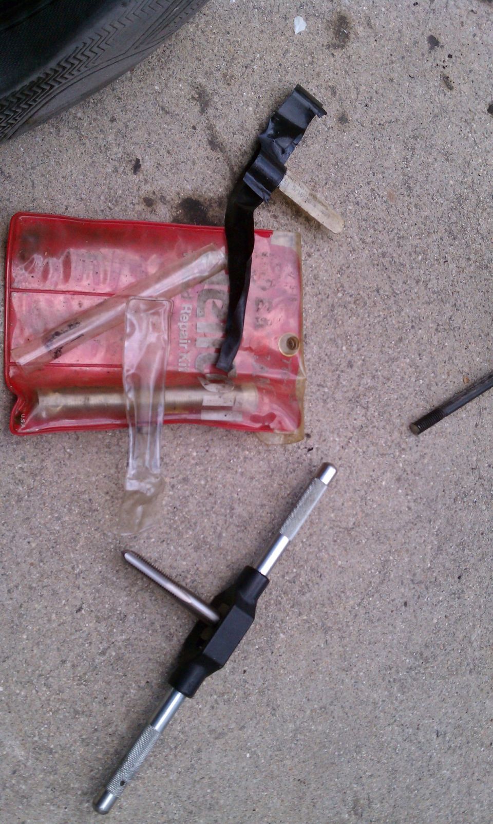 Tire repair kit with a tire tread visible in the upper left corner