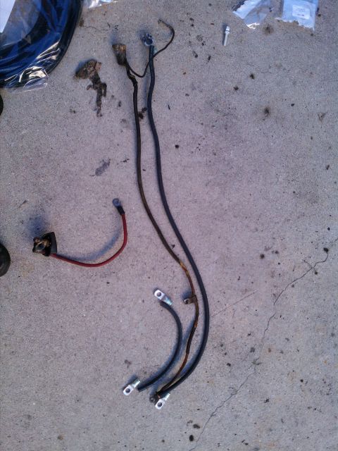 1990 Ford Bronco - Battery cables laid out on a concrete surface, possibly for a rebuild project.