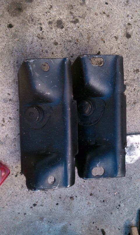 1990 Ford Bronco - Two black metal brackets are shown resting on a concrete surface.