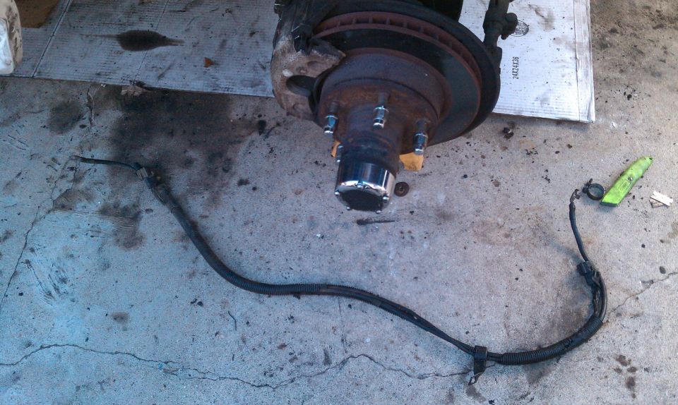 Vehicle brake rotor and hub assembly with brake line. Concrete floor with oil stains