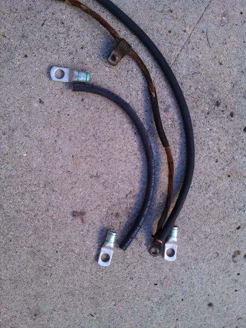 1990 Ford Bronco - These are two old battery cables, one with a frayed section, lying on concrete.